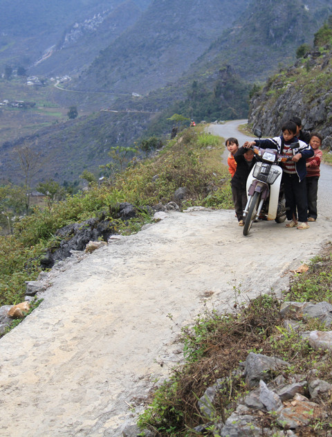Cách đó vài con dốc, một nhóm trẻ khác lại rủ nhau đẩy xe máy lên trên đường liên xã và thả dốc. Ảnh: Trường Phong