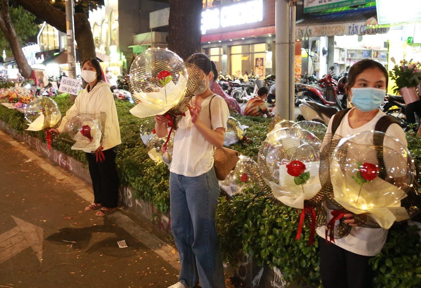Một nhóm bạn trẻ cầm những bó hoa ấn tượng chào mời khách ghé mua.