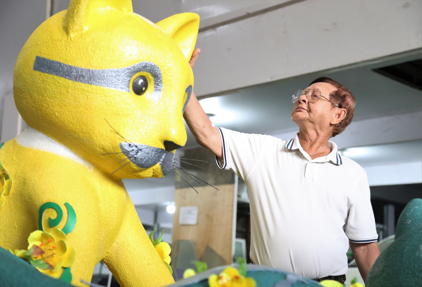 Nghệ nhân Văn Tòng bên linh vật mèo.