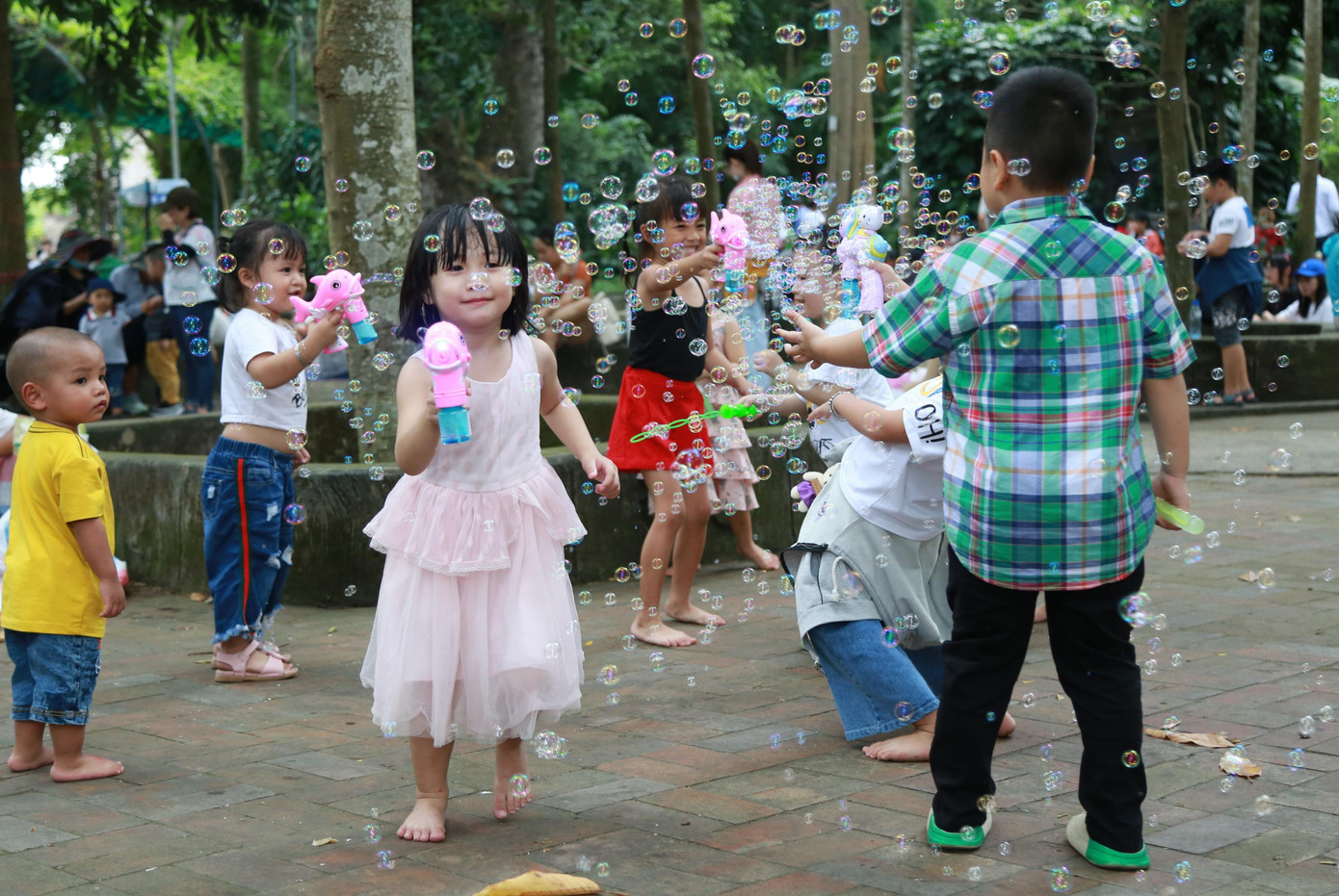Nhóm bạn nhỏ thỏa thích vui đùa cùng đồ chơi thổi bong bóng giữa công viên.