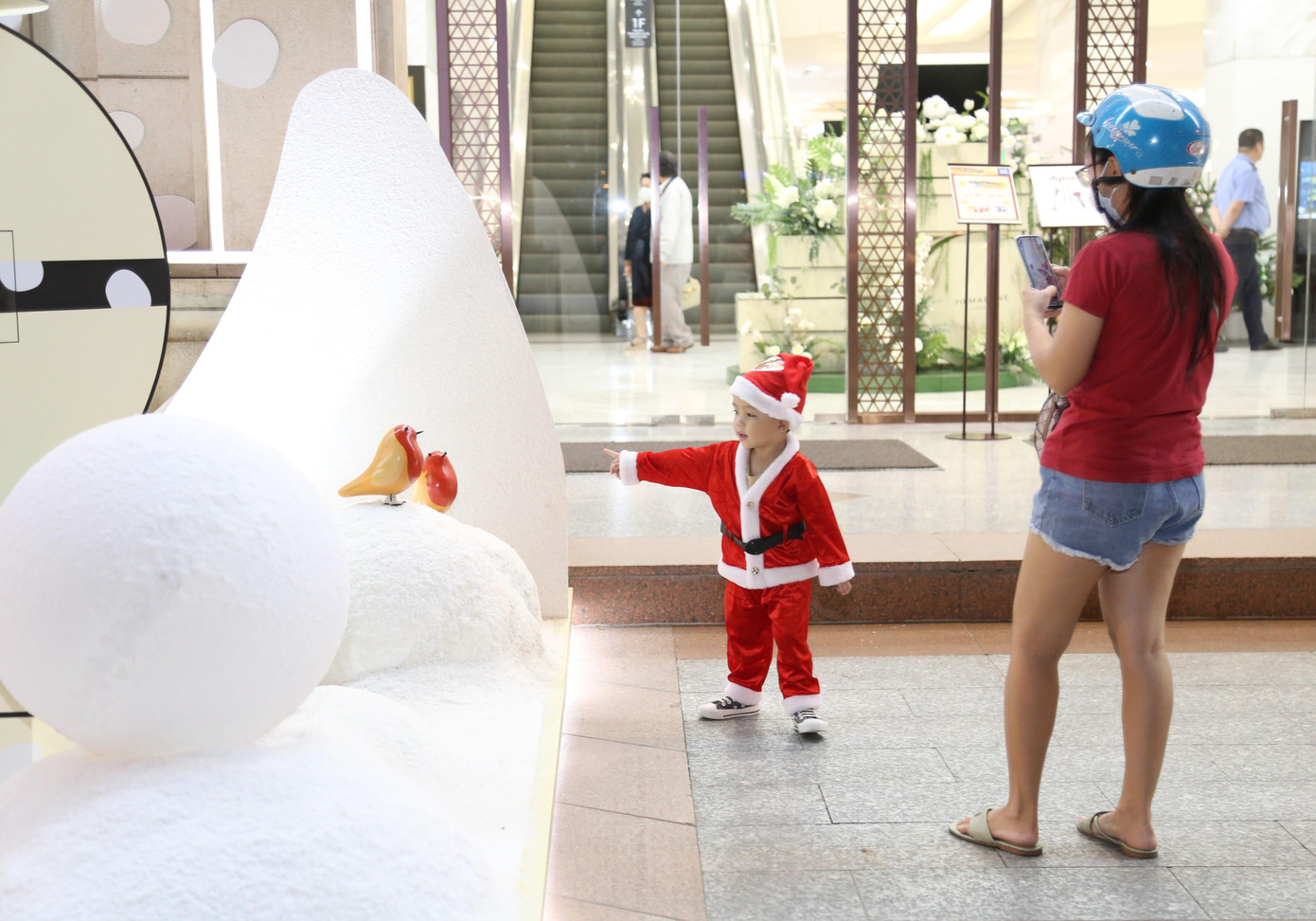 Em bé trong bộ đồ lễ hội Noel nô đùa bên không gian tuyết trắng.