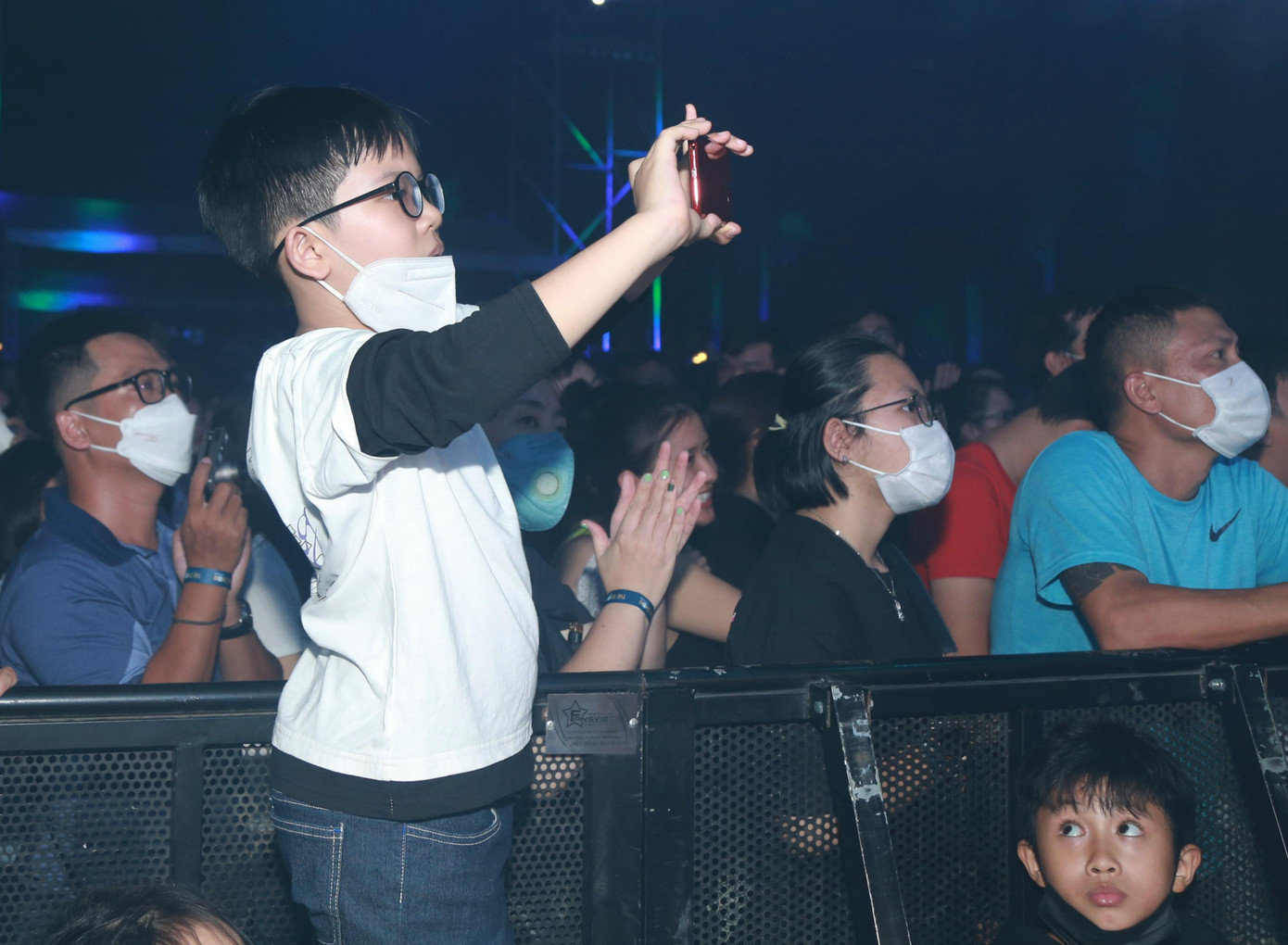 Một khán giả nhỏ tuổi ghi lại khoảnh khắc biểu diễn của các nghệ sĩ trên sâu khấu.