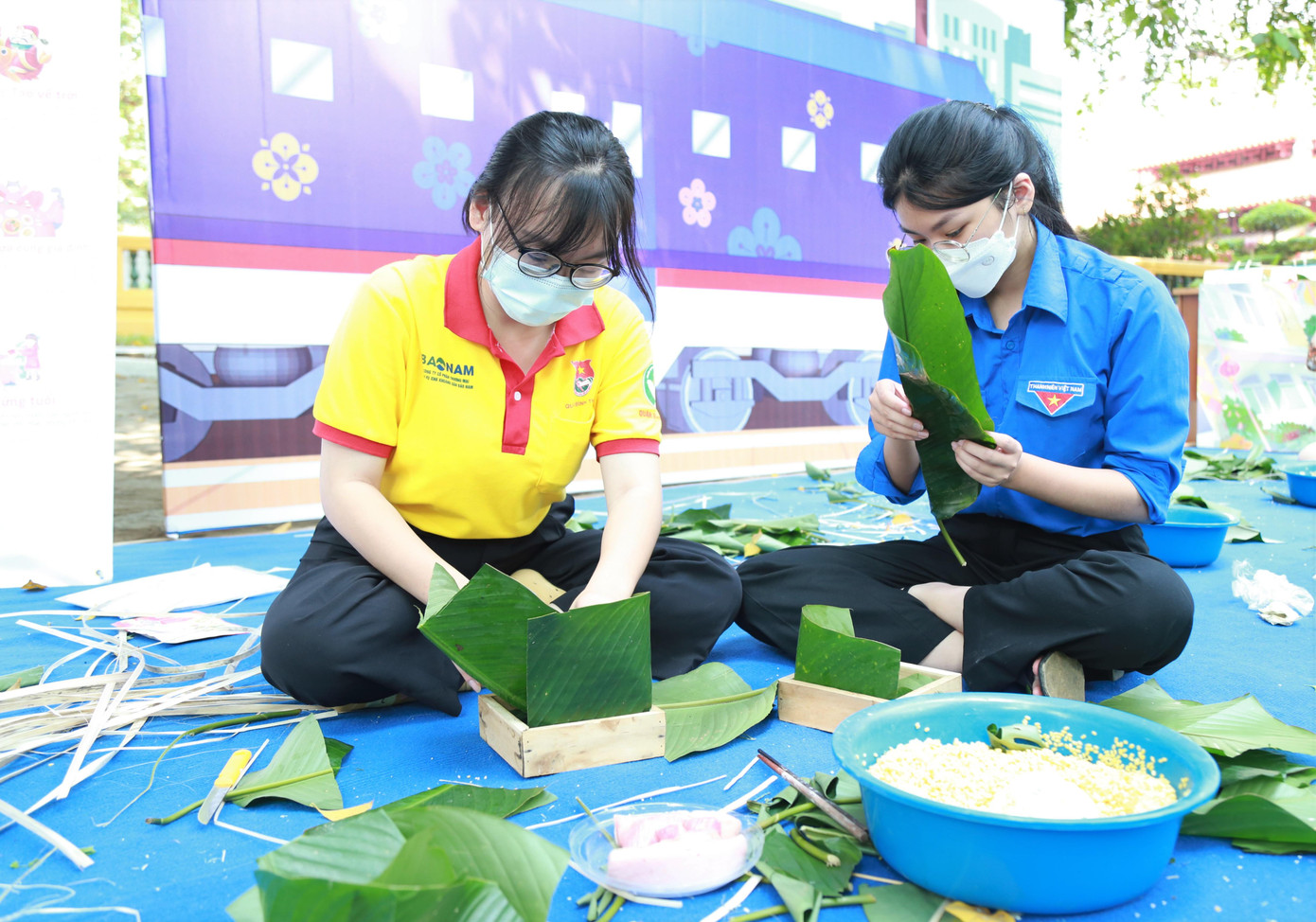 Chị Nguyễn Trương Khiết Anh (cán bộ Quận Đoàn Bình Thạnh, bìa trái) và bạn Thùy My (đoàn viên Quận Đoàn) góp sức mang lại niềm vui cho bà con dịp Tết.