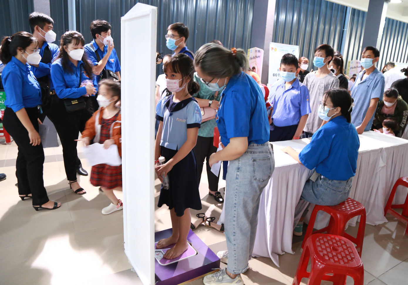Tình nguyện viên chương trình kiểm tra chỉ số chiều cao, cân nặng trước khi trẻ được thực hiện các bước sàng lọc tiếp theo.