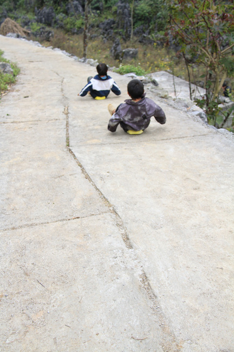 Chúng ngồi trên một chiếc can nhựa đập bẹp và lao xuống dốc. Ảnh: Trường Phong