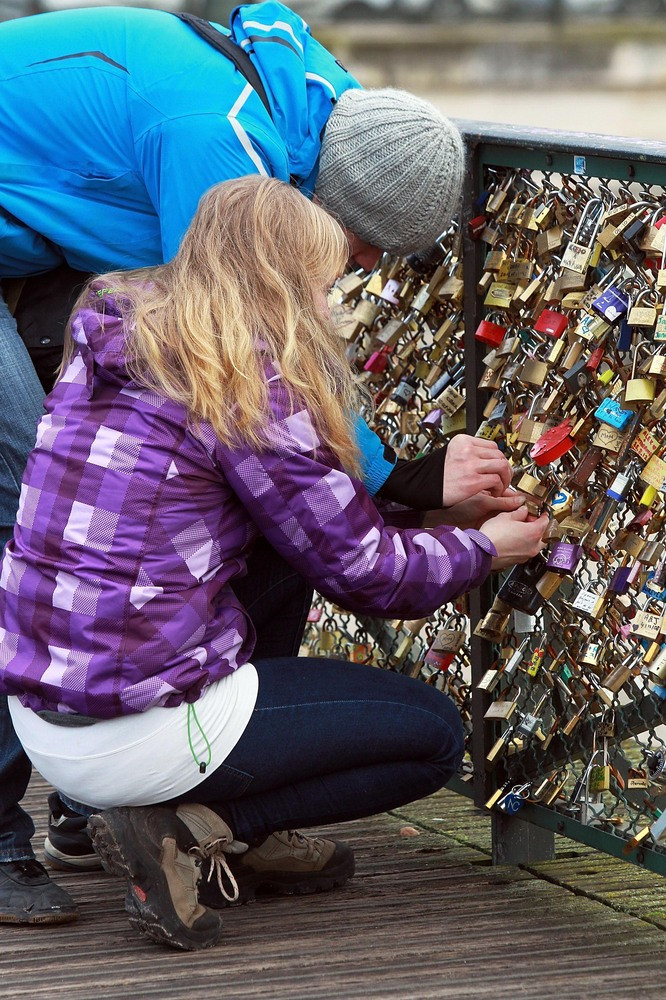 Một đôi trai gái đang tìm cách móc ổ khóa vào thành cầu 