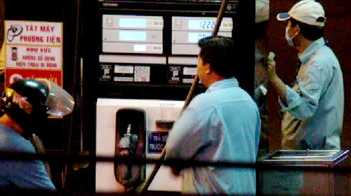 Nhân viên chuẩn bị bấm số khi một nhân viên khác đang đổ xăng cho khách