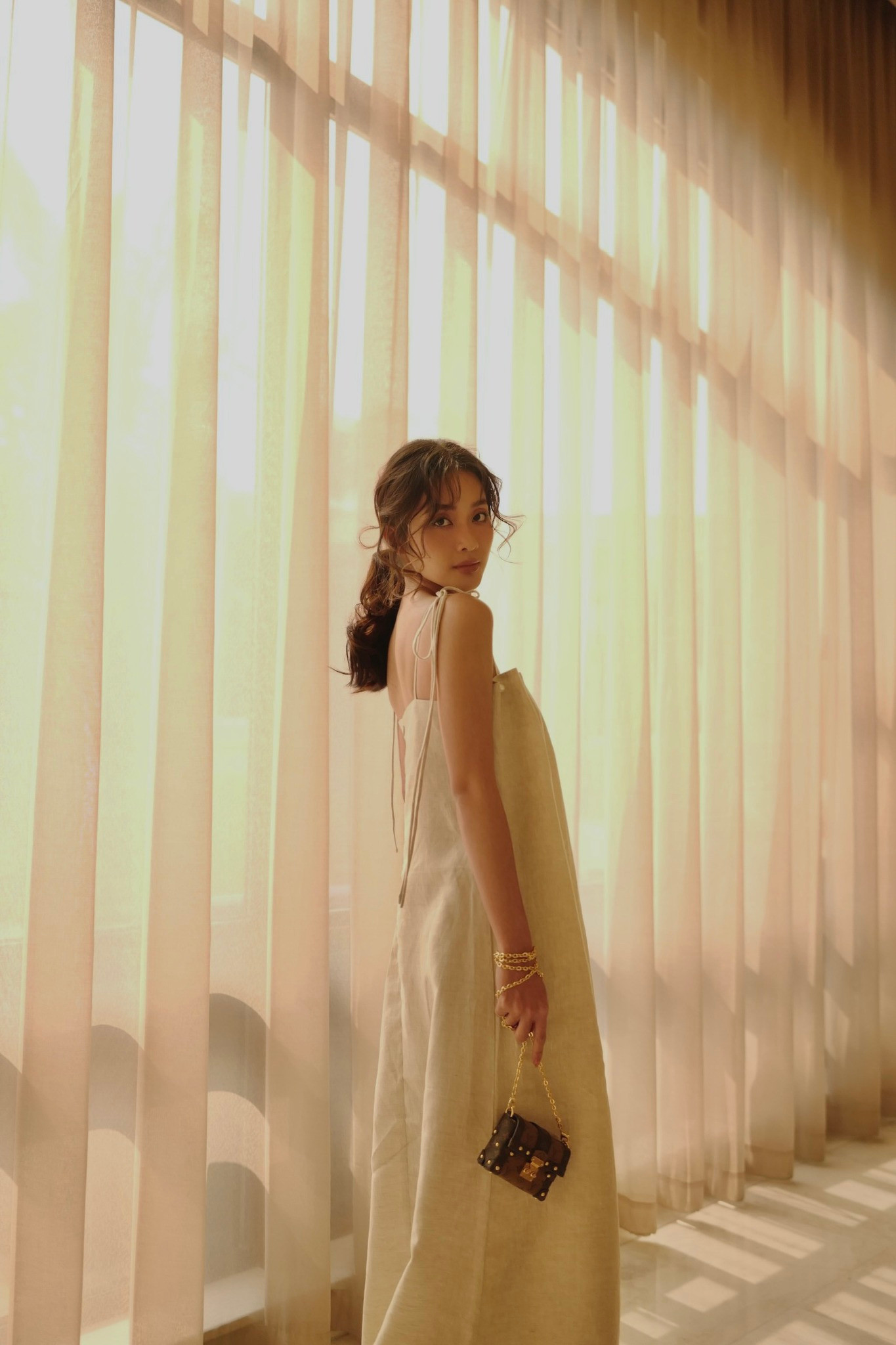 Khả Ngân khoe vẻ nữ tính trong chiếc đầm hai dây dáng babydoll. Túi xách nhỏ được nữ diễn viên sử dụng để tăng điểm nhấn cho set đồ đơn giản.