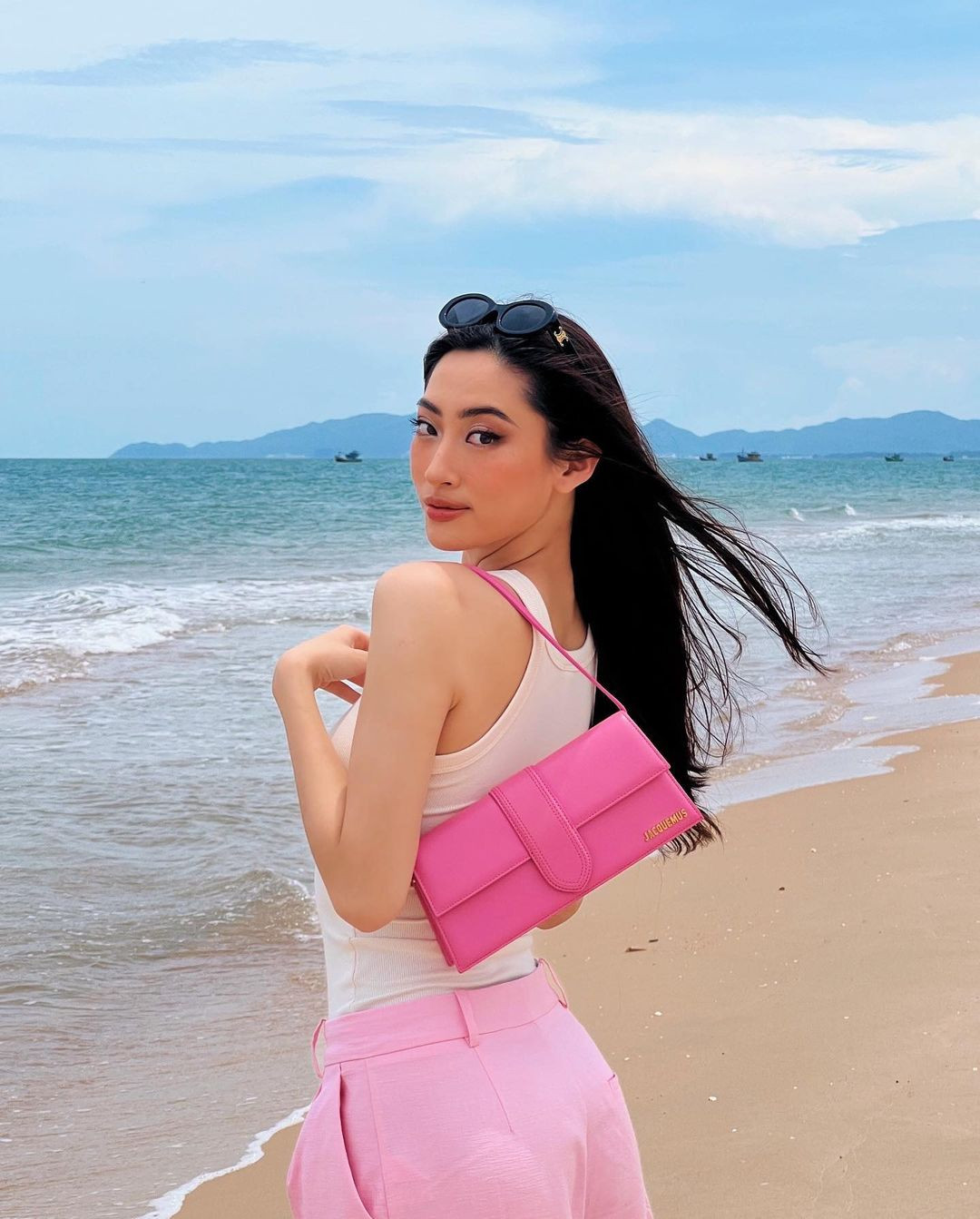Chiếc túi Jacquemus màu hồng có giá gần 20 triệu được Lương Thùy Linh kết hợp với set đồ ton sur ton để đi biển.