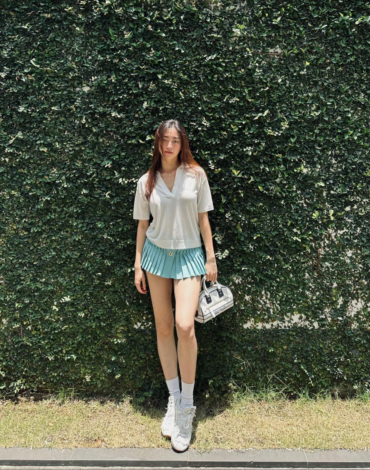 Hoa hậu Lương Thùy Linh phối áo phông đơn giản với chân váy xanh mint mát mắt khi xuống phố. Cô tạo điểm nhấn cho set đồ bằng cách chọn túi và giày sneaker ton sur ton.