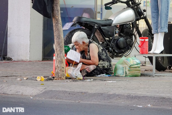 Bà Nguyễn Thị Bông ngồi đọc sách trên lề đường (Ảnh: Nguyễn Vy).
