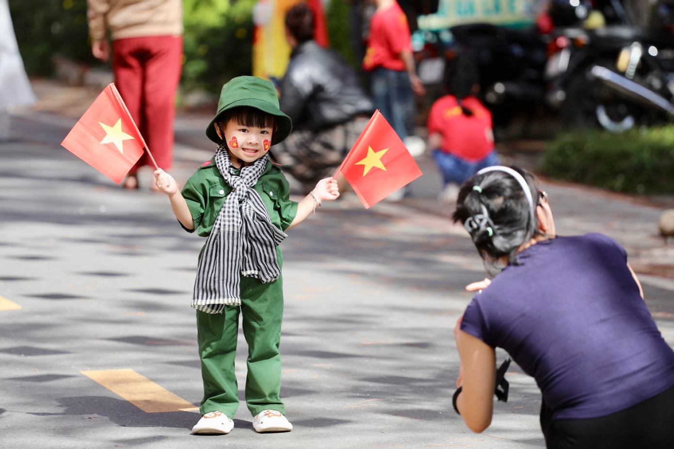 Các em bé với chiếc mũ và áo quân nhân nhỏ xinh, tay cầm cờ đỏ sao vàng, tạo nên hình ảnh vô cùng dễ thương.