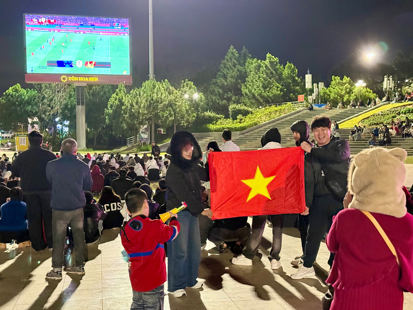 Một du khách Hàn Quốc phấn khởi cầm quốc kỳ Việt Nam check-in cùng các cổ động viên