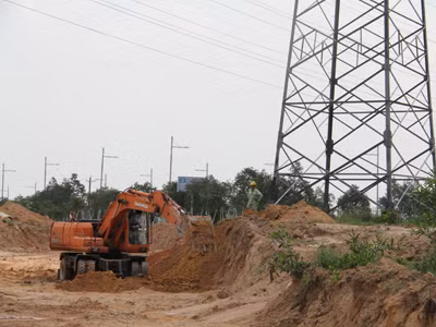 Một chiếc xe xúc gặm sát vào chân một cột điện 500 KV tại thành phố mới Bình Dương. Ảnh: Đại Dương 