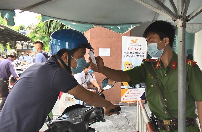 Tại điểm cấp căn cước, người dân được đo thân nhiệt trước khi vào làm.