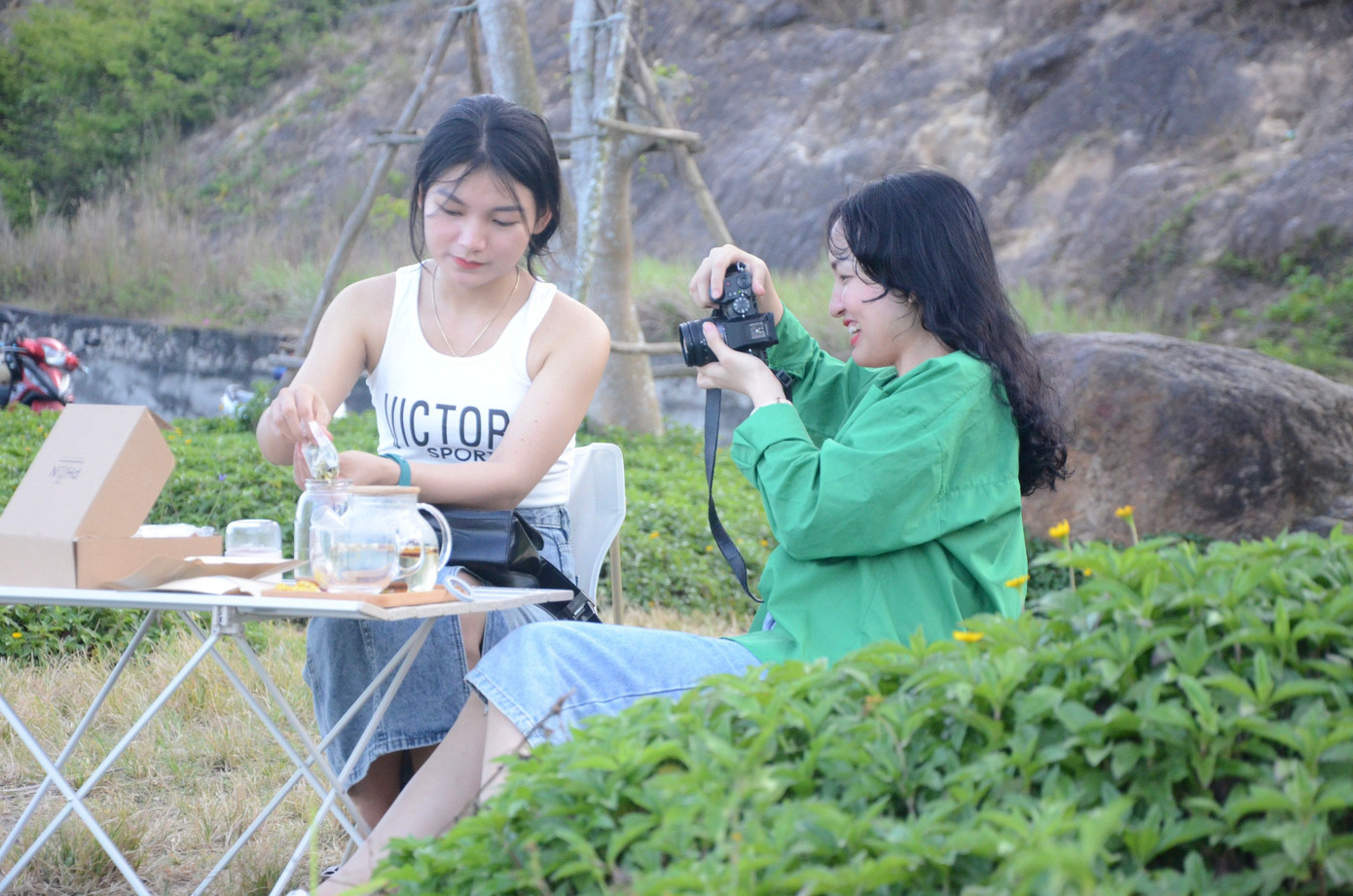 Tham quan được vài nơi trên bán đảo nhưng nắng nóng, bạn Lê Thị Trình (du khách Huế) cùng bạn tìm chỗ gốc cây để ngồi nghỉ, hóng gió.