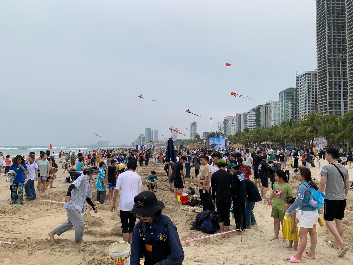 Từ trưa, hàng trăm người là sinh viên, người dân và du khách đã có mặt tại bãi biển để chuẩn bị cho cuộc thi đắp cát. Ảnh: Thái Lâm.