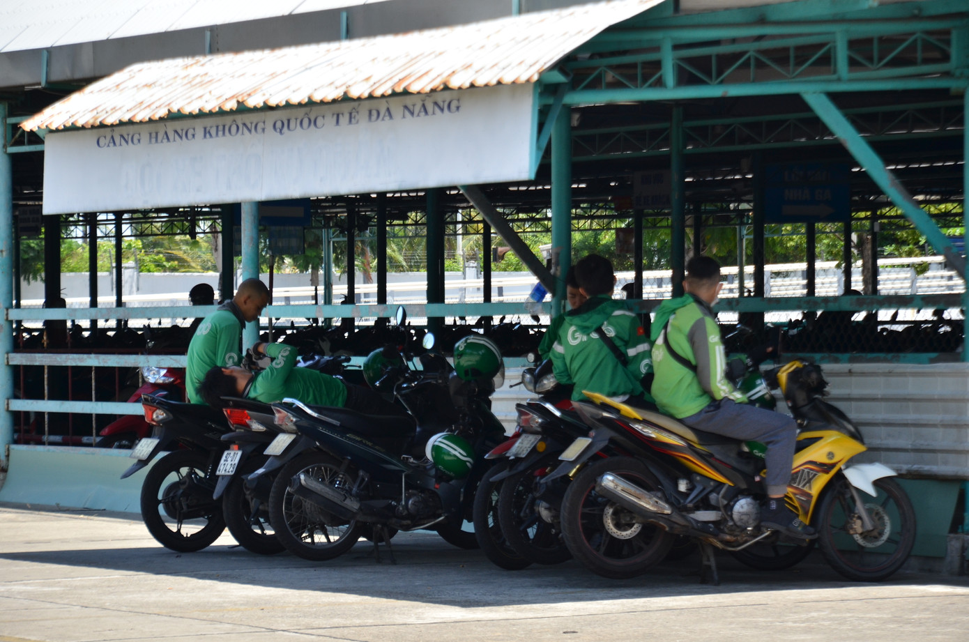 Những tài xế chạy xe công nghệ tranh thủ nghỉ ngơi nơi bóng mát vào giữa trưa nắng.