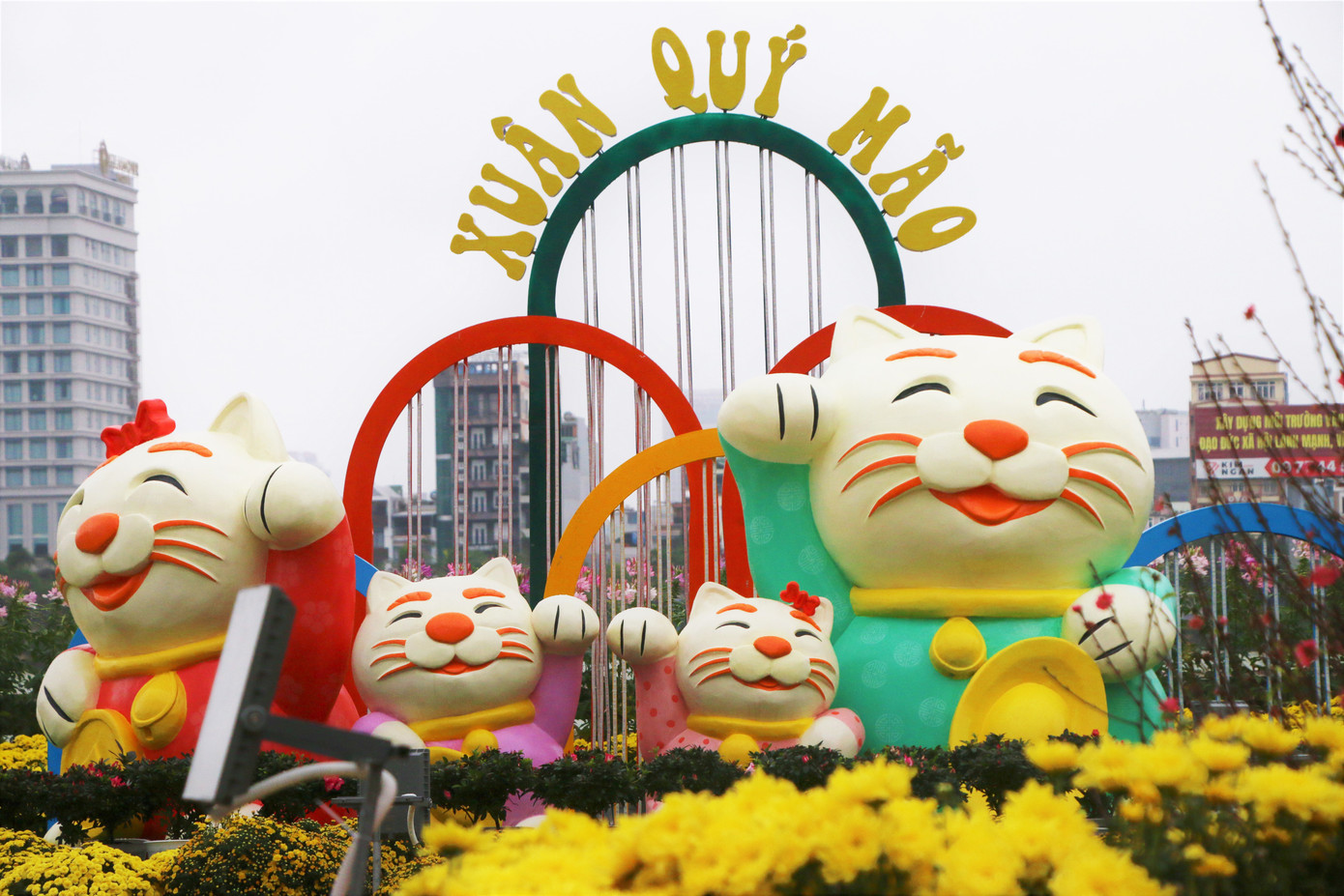 Luôn là điểm nhấn được mọi người quan tâm, linh vật mèo năm nay được thiết kế dễ thương, khiến nhiều người dân và du khách trầm trồ và thích thú. Trong ảnh: Một gia đình mèo mặc đồ truyền thống ôm thỏi vàng tại vườn hoa đường Bạch Đằng.