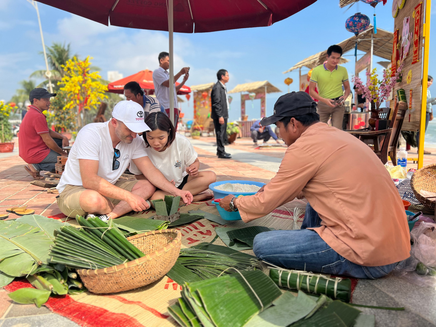 Du khách nước ngoài gói bánh chưng dưới sự hướng dẫn của các nghệ nhân (Ảnh: Thái Lâm).