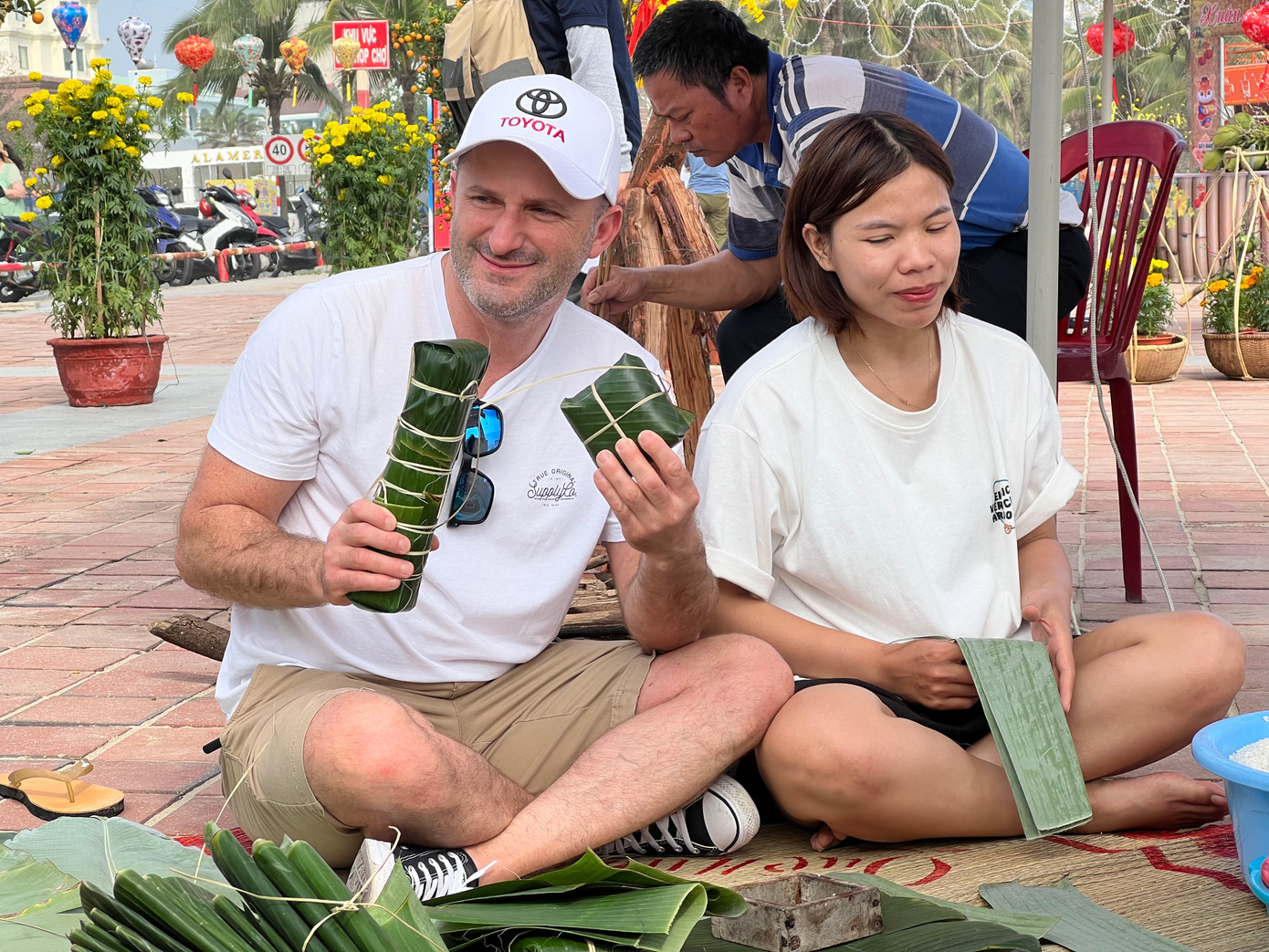 Anh du khách nước ngoài khoe thành tích của mình sau một hồi loay hoay gói bánh chưng và bánh tét cùng các nghệ nhân.