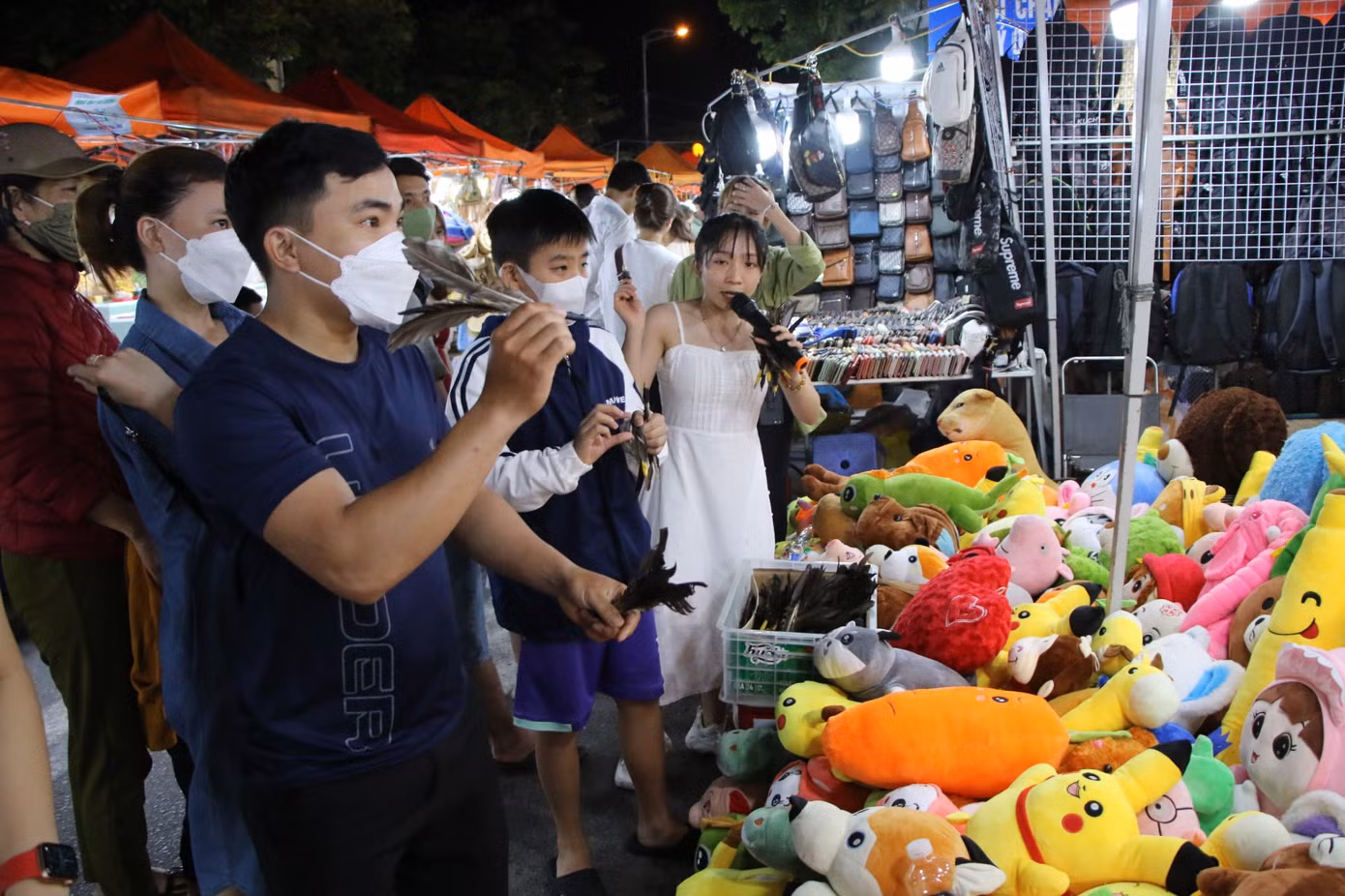 Gian hàng trò chơi ném bóng bay nhận thú bông thu hút nhiều du khách, tạo nên không khí nhộn nhịp tại chợ.