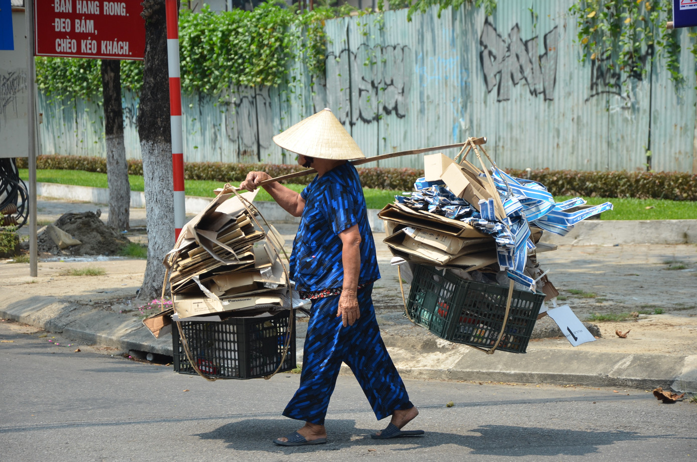 12 giờ trưa, bà cụ hơn 80 tuổi đi dọc các tuyến đường có cửa hàng để nhặt nhạnh giấy vụn, phế liệu.