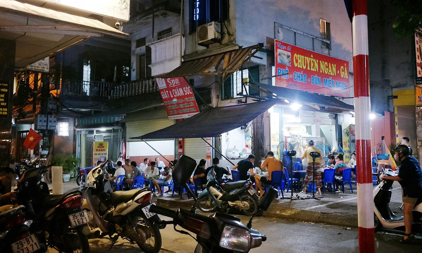 Cách đó không xa, hàng ăn trên mặt phố Tân Mai (Hoàng Mai) có hàng chục khách đang ăn uống. Bàn ăn được xếp cạnh nhau trên vỉa hè. Cách đó không xa, hàng ăn trên mặt phố Tân Mai (Hoàng Mai) có hàng chục khách đang ăn uống. Bàn ăn được xếp cạnh nhau trên vỉa hè.