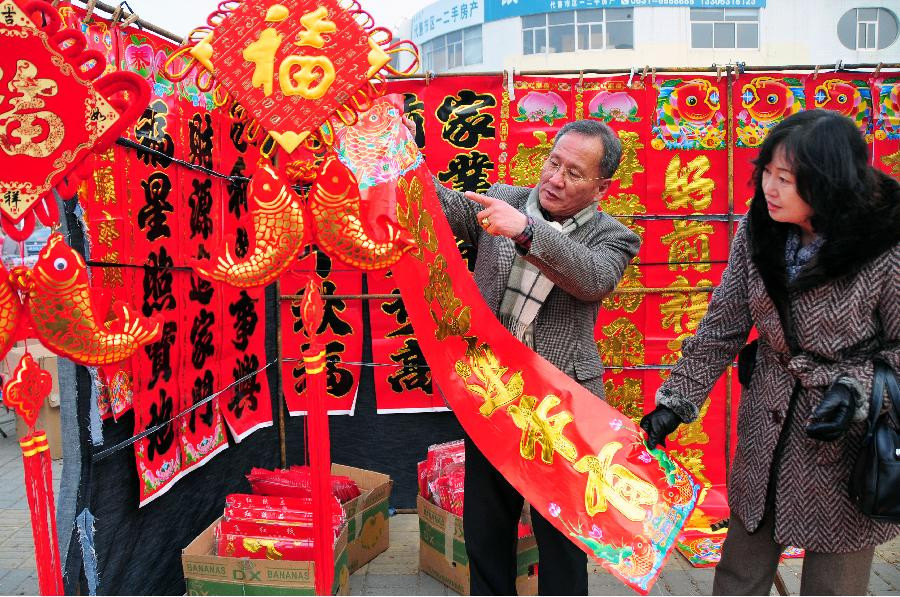 Ông Byungcho Kim cùng vợ sống tại tỉnh Sơn Đông đi chọn câu đối đỏ cho ngày Tết. Ảnh: Xinhua