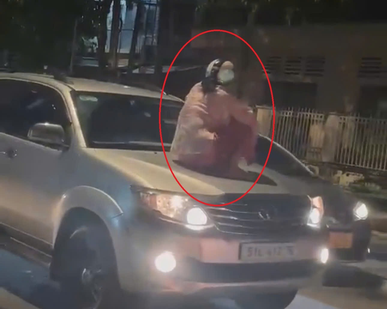 Người phụ nữ ngồi trên nắp capo ô tô đang chạy.