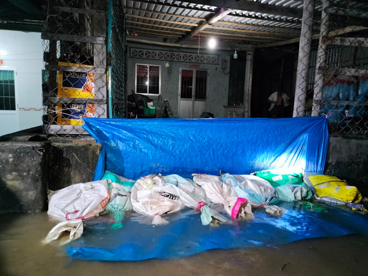 Người dân dùng bao cát, tấm bạt che chắn ngăn nước chảy vào nhà.