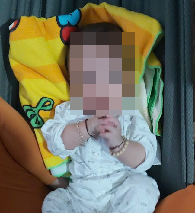 Bé trai bị bỏ rơi ven đường đang được người phụ nữ phát hiện chăm sóc.