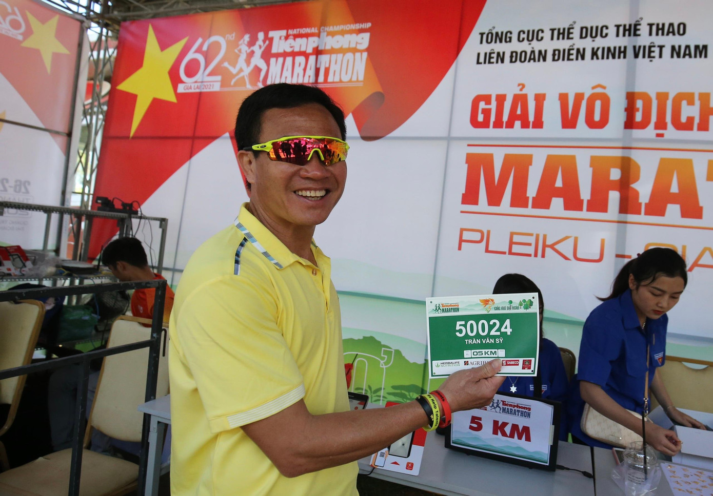 HLV đội tuyển điền kinh quốc gia Trần Văn Sỹ hào hứng nhận BIB. Không chỉ dẫn dắt các học trò đoàn Thanh Hoá dự giải, ông Sỹ sẽ tranh tài trên đường chạy marathon khắc nghiệt với tư cách VĐV phong trào. Đây là lần thứ hai ông Sỹ thi đấu tại Tiền Phong Marathon. Trong điều kiện khắc nghiệt trên đảo Lý Sơn năm ngoái, ông Sỹ đã xuất sắc đứng thứ hai lứa tuổi trên 45 tuổi ở cự ly bán marathon.