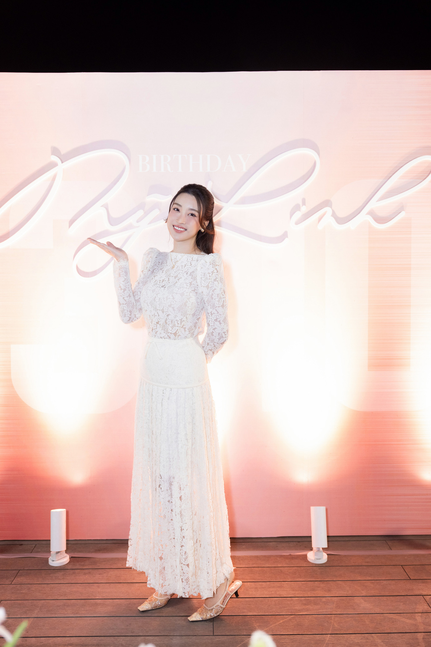 Hoa hậu Việt Nam 2016 mặc bộ váy ren trắng thanh lịch, kín đáo, đi giày thấp. Đây là lần xuất hiện đầu tiên của Đỗ Mỹ Linh kể từ khi sinh con đầu lòng hồi tháng 7.