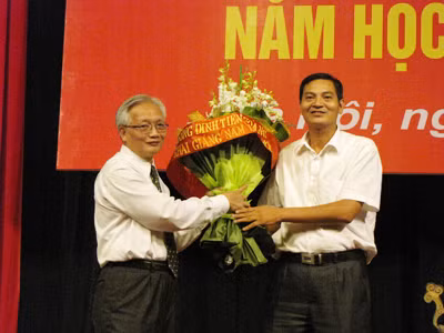 Tiến sĩ Nguyễn Tùng Lâm, hiệu trường trường THPT Đinh Tiên Hoàng (bên trái) nhận bó hoa tri ân của đại diện phụ huynh học sinh