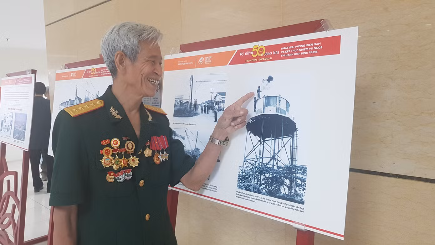 Ông Phạm Văn Lãi bên tấm ảnh cắm cờ giải phóng ngày 30/4/1975 tại Trại Davis Ảnh: KIẾN NGHĨA
