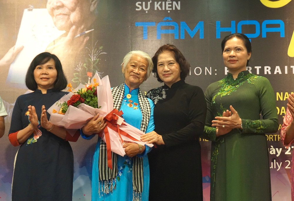 Hoạ sĩ Đặng Ái Việt tại triển lãm “Tâm họa tri ân”, được tổ chức ở Bảo tàng Phụ nữ Việt Nam cuối tháng 7/2024. Bên cạnh họa sĩ Ái Việt là nguyên Chủ tịch Quốc hội Nguyễn Thị Kim Ngân