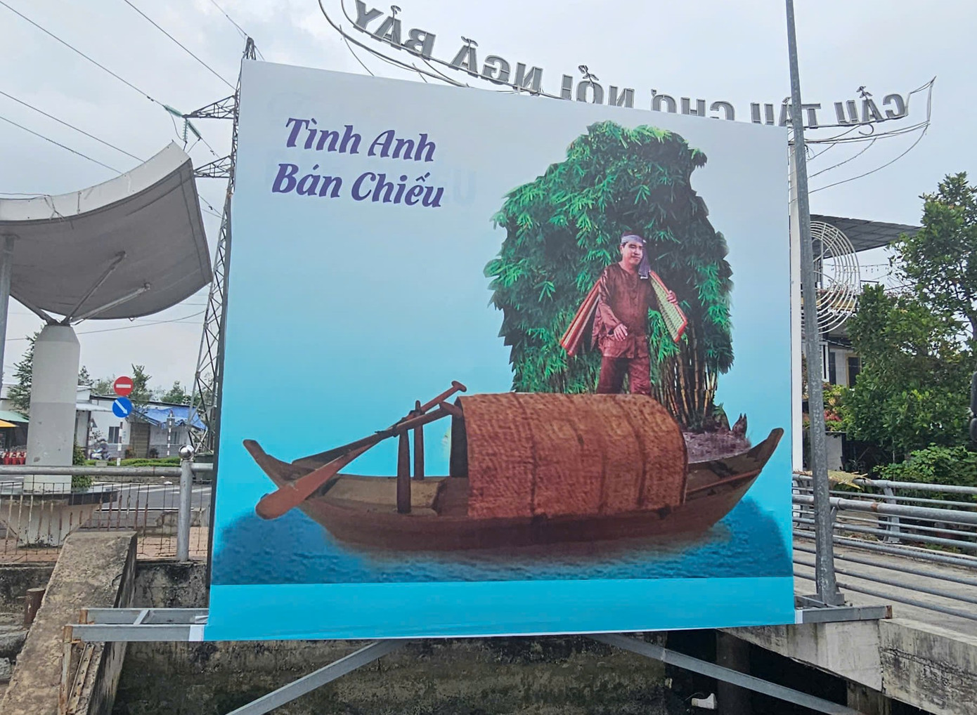 Bức tranh có dòng chữ “Tình anh bán chiếu” với hình ảnh người đàn ông vác đôi chiếu trên vai đứng trên ghe đặt ở mé bờ. Ảnh: Hòa Hội