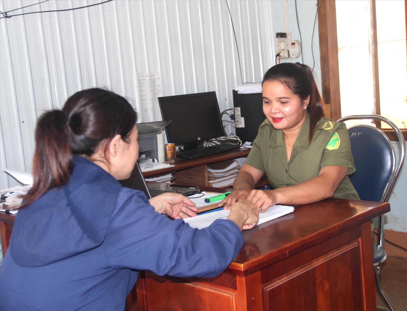 Nữ công an viên H’Oanh (bìa phải) hướng dẫn người dân làm căn cước công dân.