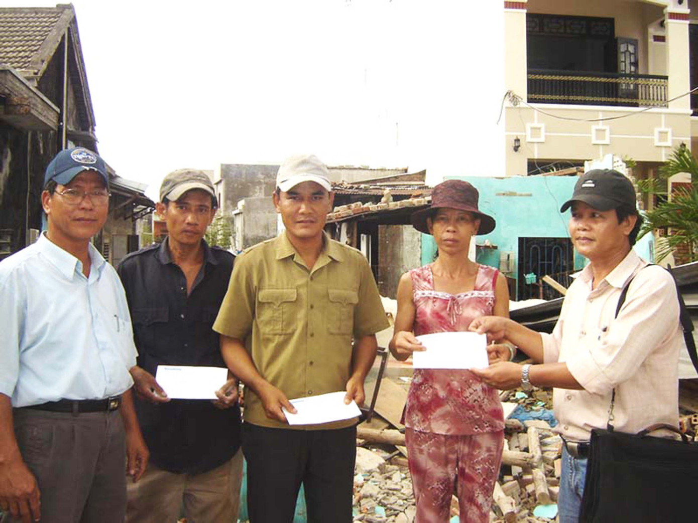 Anh Lê Công Đỉnh (bìa phải) thay mặt báo Tiền Phong tại miền Trung trao hỗ trợ cho những gia đình bị thiệt hại do bão Sangxane - Đà Nẵng năm 2006 (Ảnh: Nguyễn Huy)