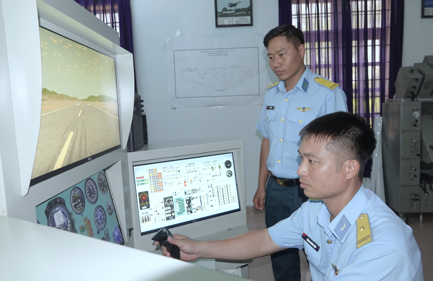 Chính trị viên Phi đội 2 Đặng Hoàng Hiệp (người ngồi) thực hiện bay đội trưởng trên buồng tập lái mô phỏng Su-22 tại Trung đoàn Không quân 937, đứng bên cạnh là Phó Phi đội trưởng Lê Văn Tùng