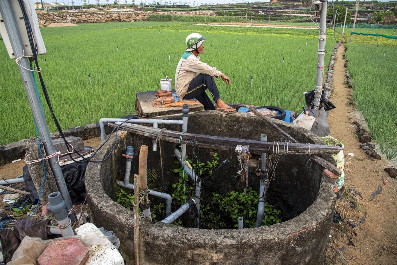 Lão nông Võ Hiển Vinh đang chờ bơm chạy vài phút rồi lại đi giếng khác bật cầu dao Ảnh: Văn Chương Lão nông Võ Hiển Vinh đang chờ bơm chạy vài phút rồi lại đi giếng khác bật cầu dao Ảnh: Văn Chương