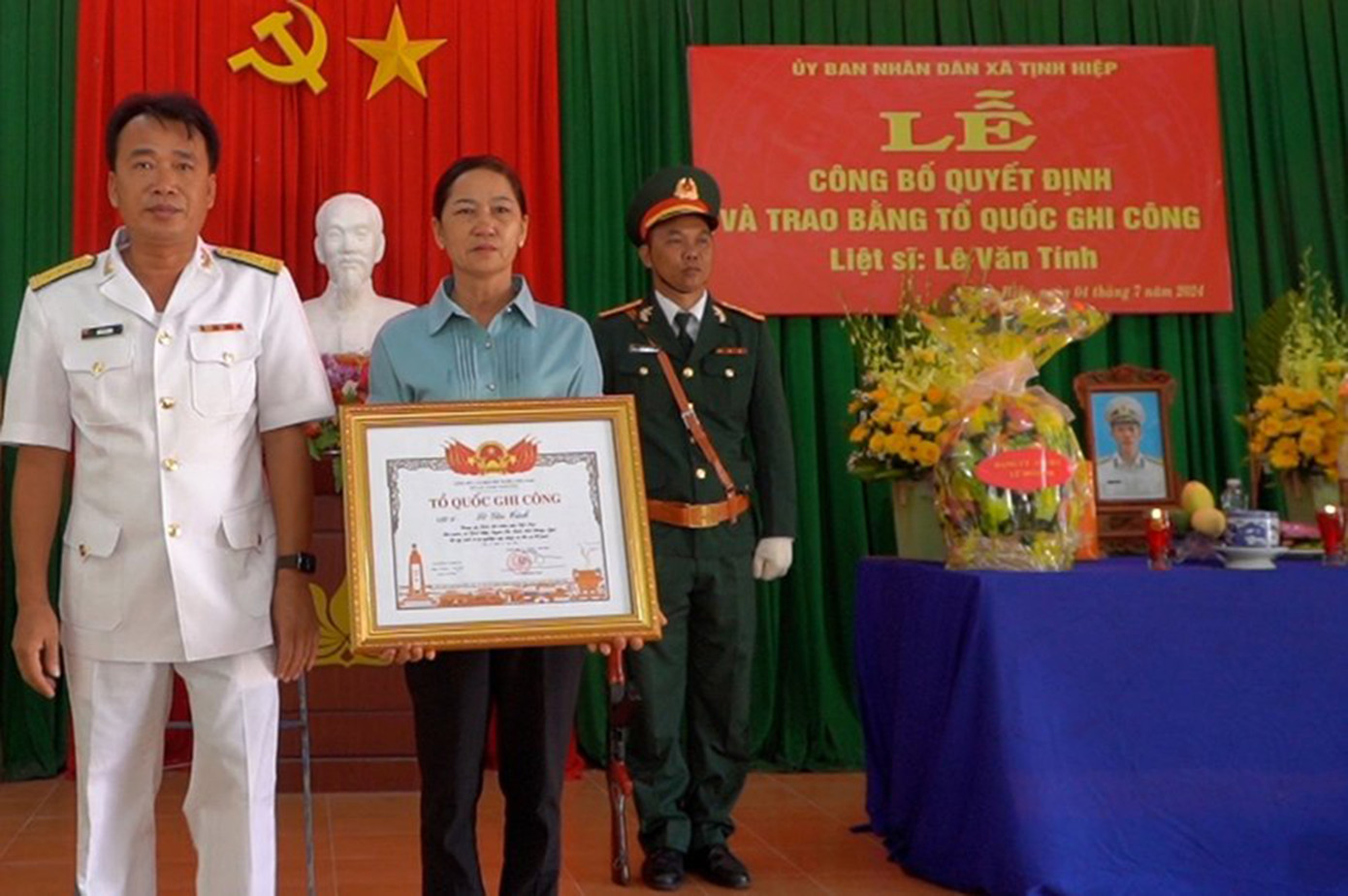 Bà Vân thay mặt gia đình đón nhận Bằng Tổ quốc ghi công cho con trai là liệt sĩ Lê Văn Tính ảnh: GĐCC
