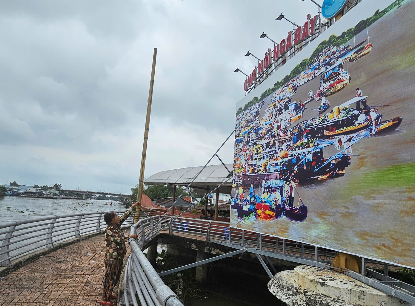 Bà Nguyễn Thị Nga chỉ tay về bức ảnh chợ nổi Ngã Bảy thời đông đúc có bà trong đó. Ảnh: Hòa Hội