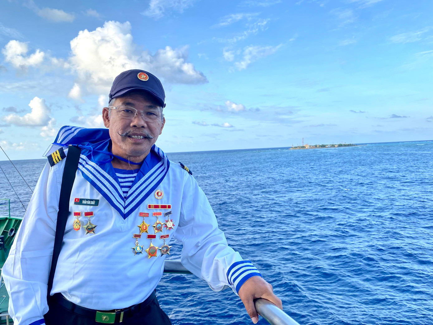 Cựu chiến binh đảo Trường Sa Đông Trần Văn Xuất trên tàu HQ 571. Phía sau, bên phải ông là đảo Trường Sa Đông