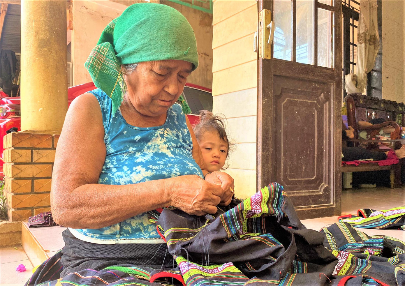 Cụ H’Ti BKrông miệt mài tra hạt cườm vào trang phục thổ cẩm.