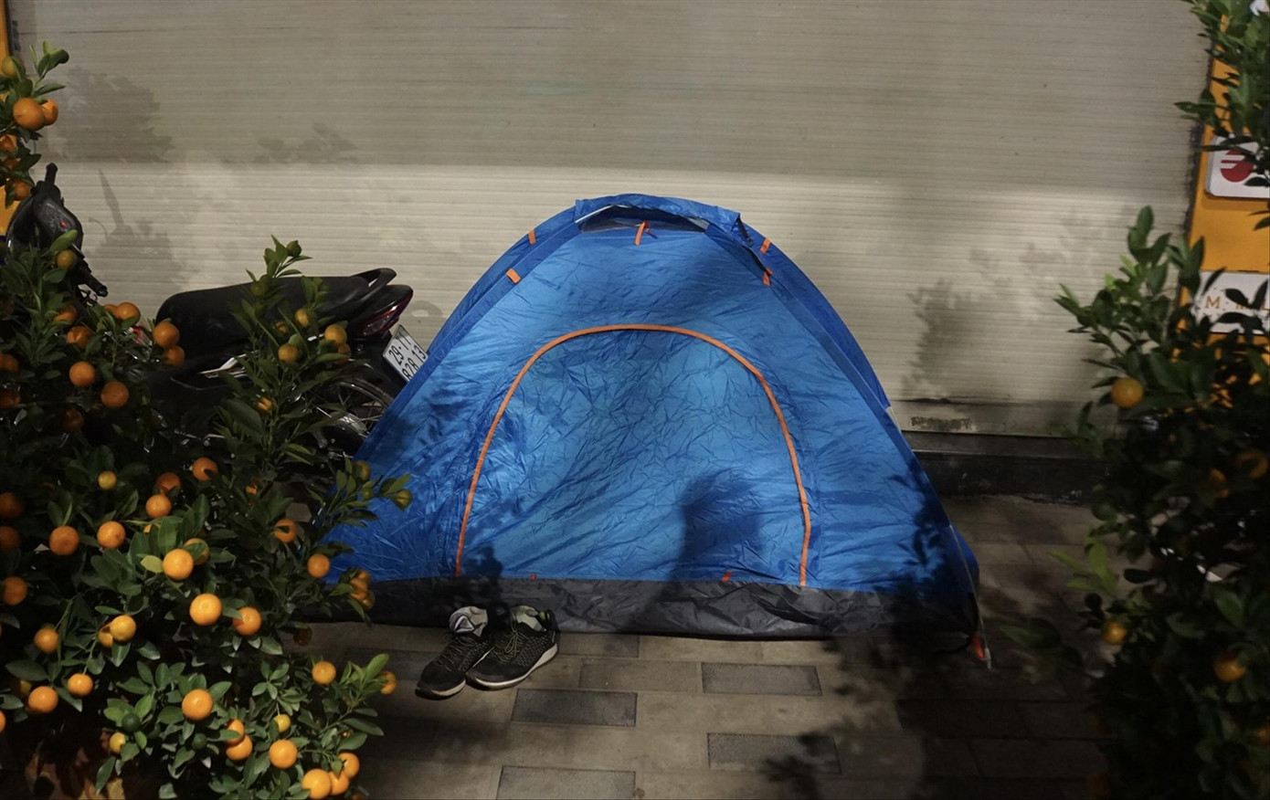 Căn lều dựng tạm từ những thanh gỗ, tre, được phủ bạt và áo mưa làm mái của anh Lê Văn Lương và chị Nguyễn Thị Phượng Căn lều dựng tạm từ những thanh gỗ, tre, được phủ bạt và áo mưa làm mái của anh Lê Văn Lương và chị Nguyễn Thị Phượng