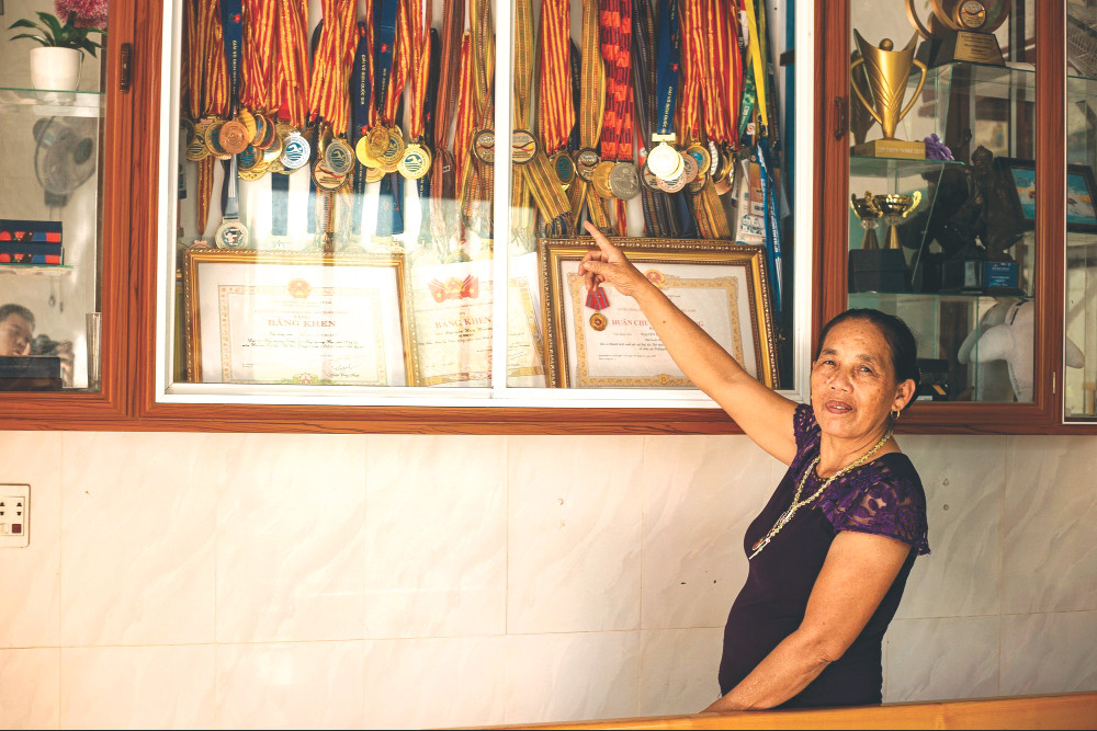 Bà Nguyễn Thị Học bên tủ huy chương của con trai