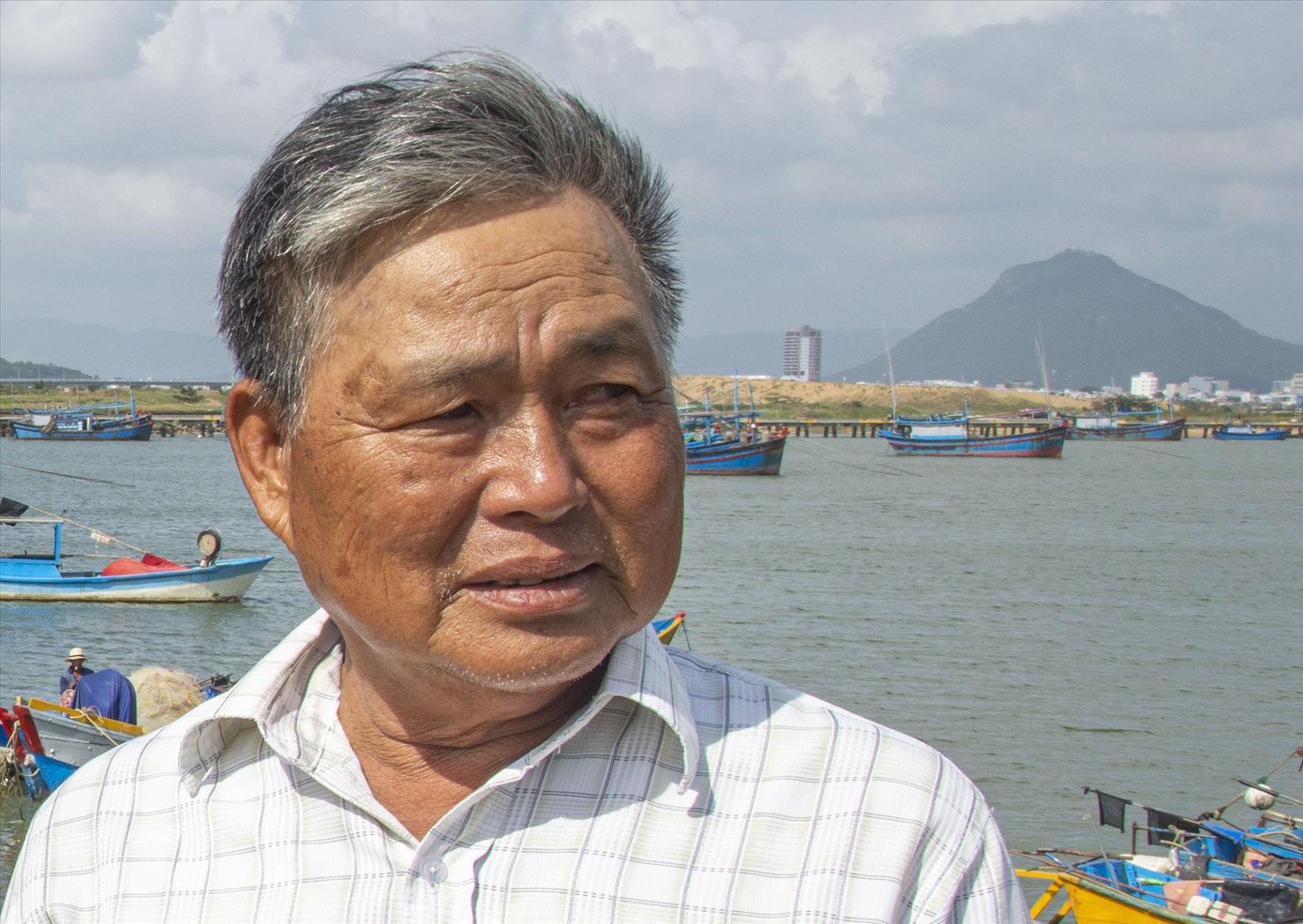 Lão ngư dân Huỳnh Văn Thắng, cha ngư dân thuyền trưởng Huỳnh Đức Lợi vừa mất tích trên biển. Phía sau là hòn Chóp Chài - Ảnh: Văn Chương