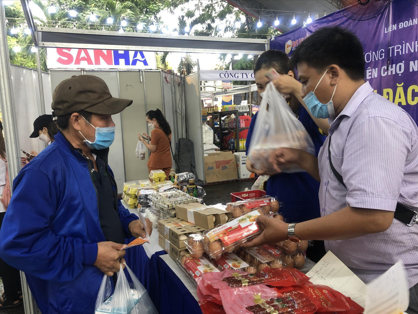Trong bộ đồ công nhân, anh Nguyễn Hoàng Ngải (bên trái) vui mừng vì được tặng phiếu mua sắm tại phiên chợ nghĩa tình hôm 29/4